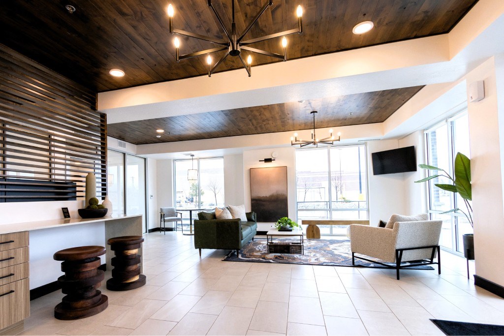 A modern living room with a dark wood ceiling and white walls.