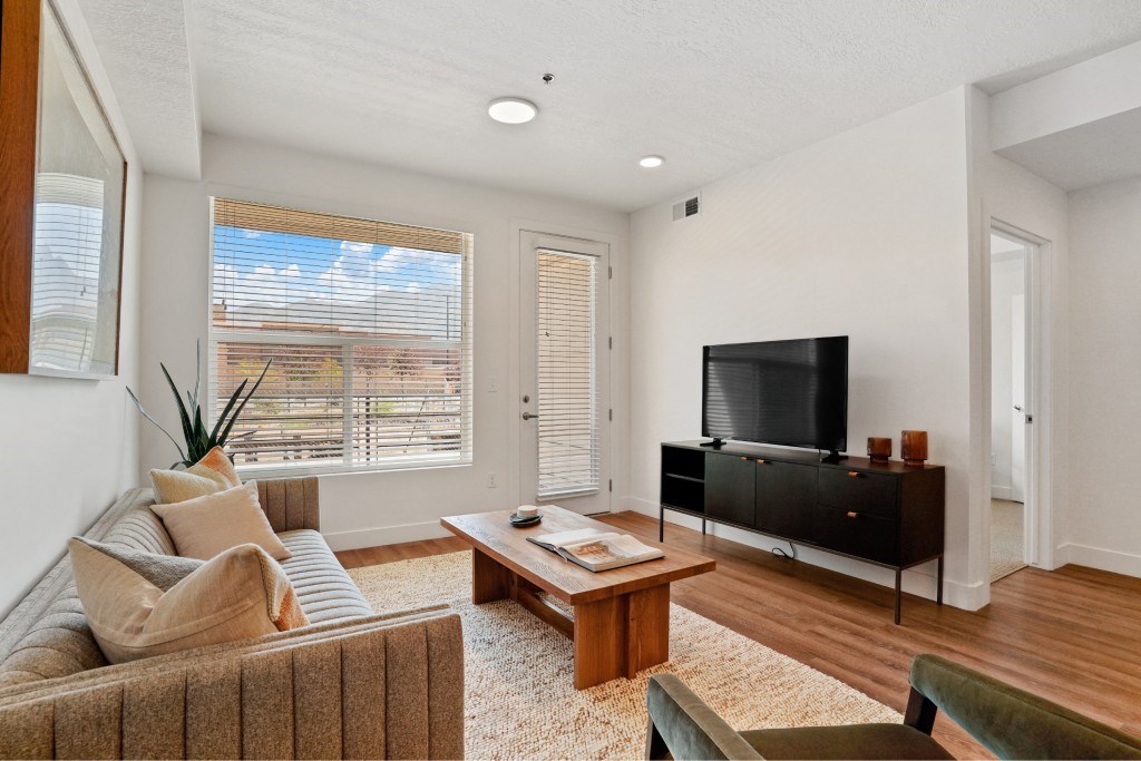 A living room with a brown couch, a wooden coffee table, and a flat screen TV.