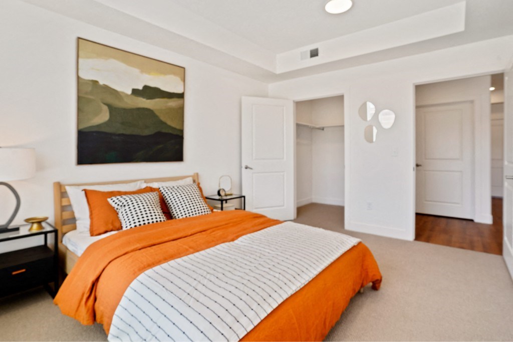 A bedroom with a bed, a nightstand, and a painting on the wall.