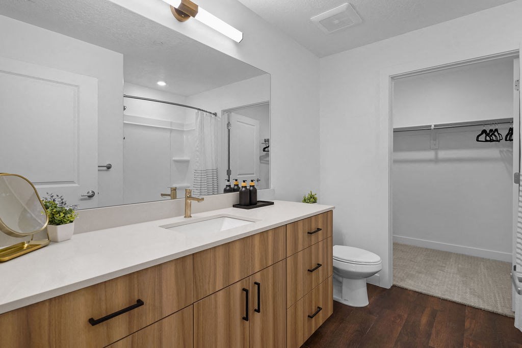 A bathroom with a white counter top and wooden cabinets.