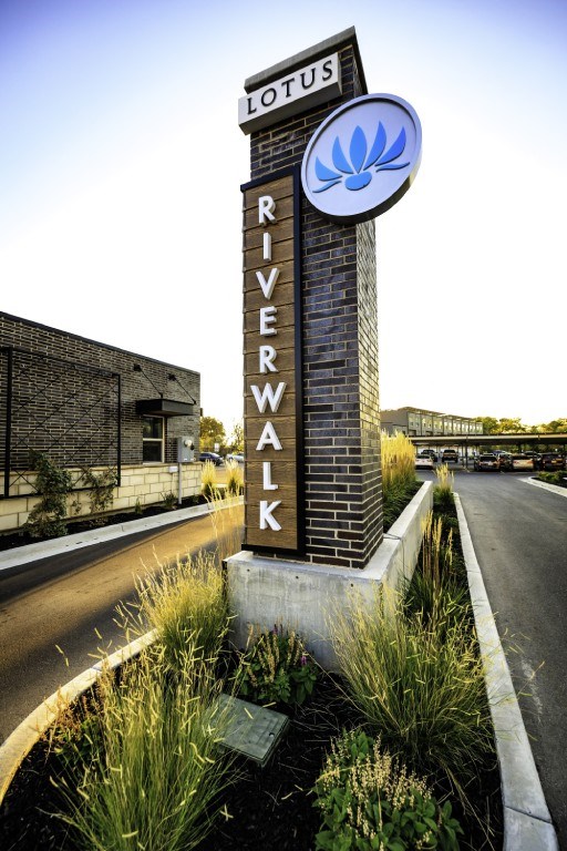 A sign for Riverwalk Lotus stands in front of a building.