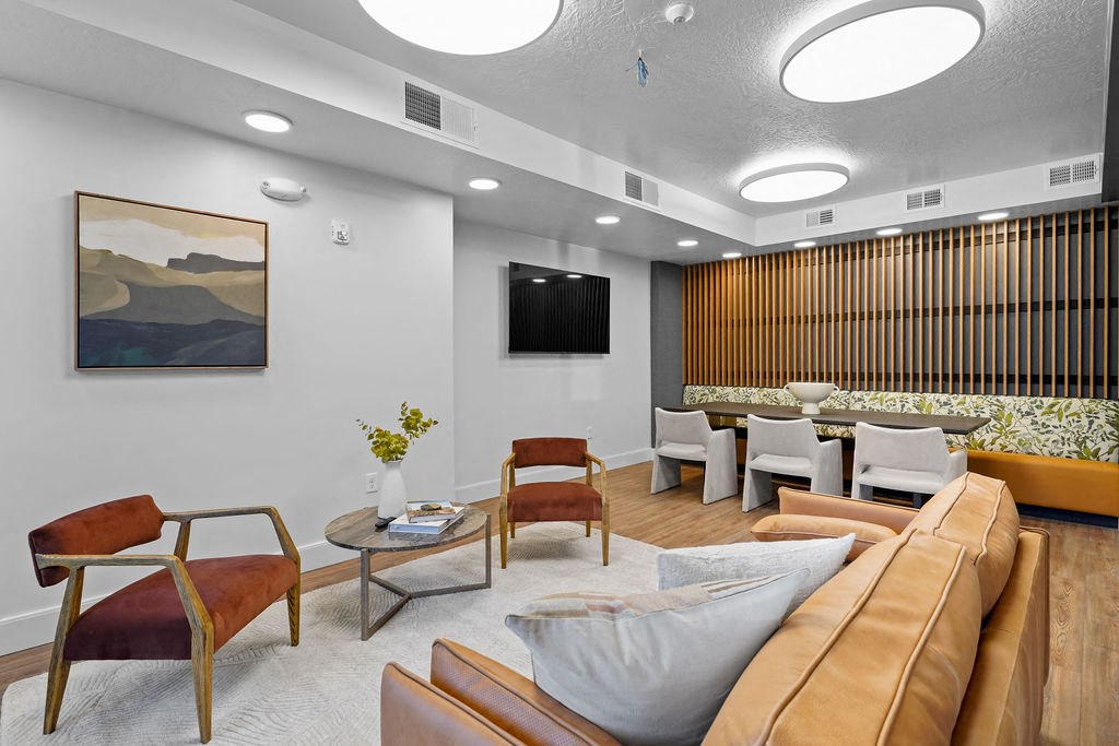 A living room with a brown leather couch and a painting on the wall.