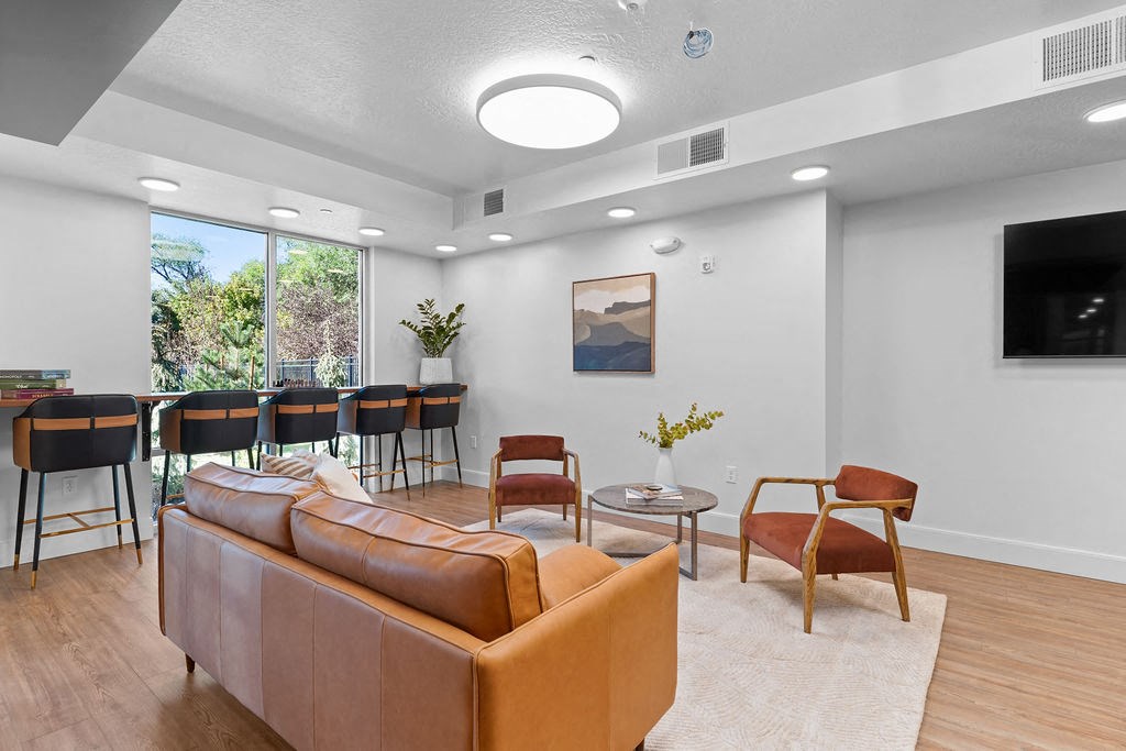 A living room with a brown sofa and a painting on the wall.