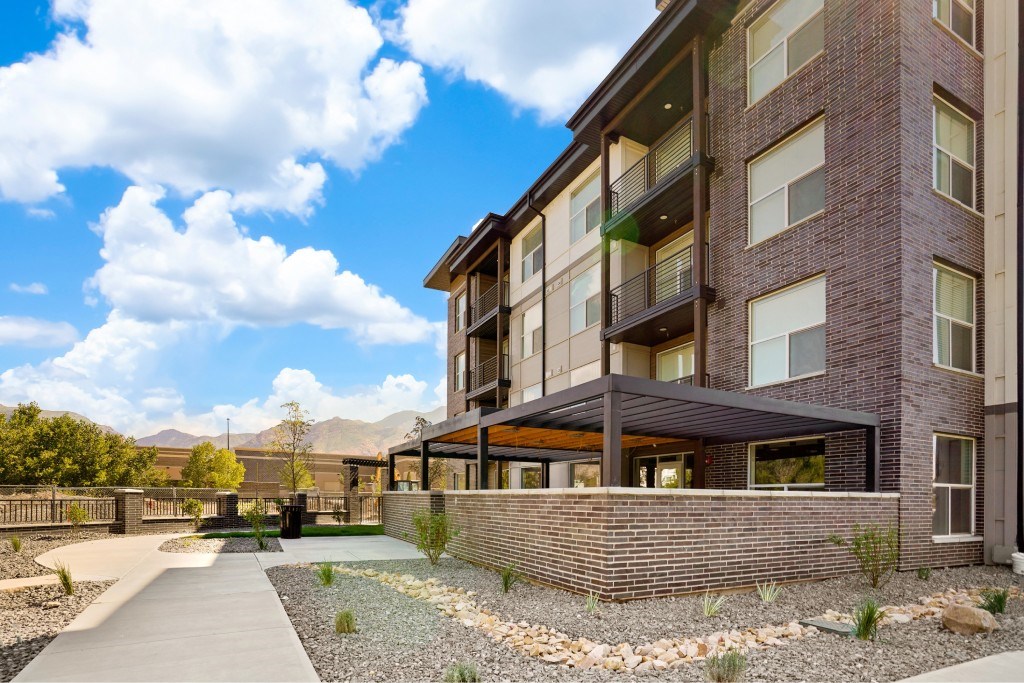 A modern brick building with a balcony and a gravel garden in front.