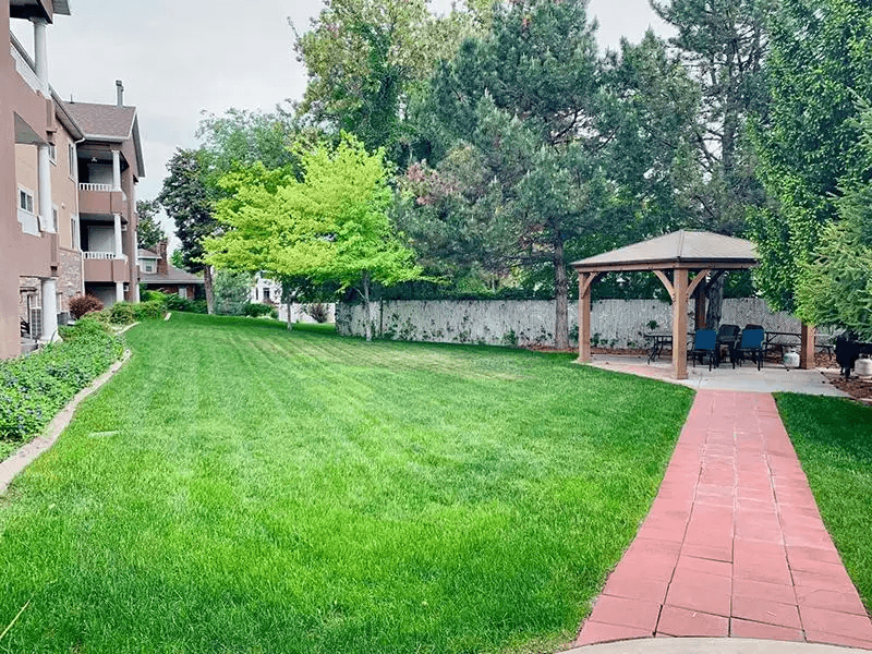 A grassy area with a red brick walkway leading to a gazebo.