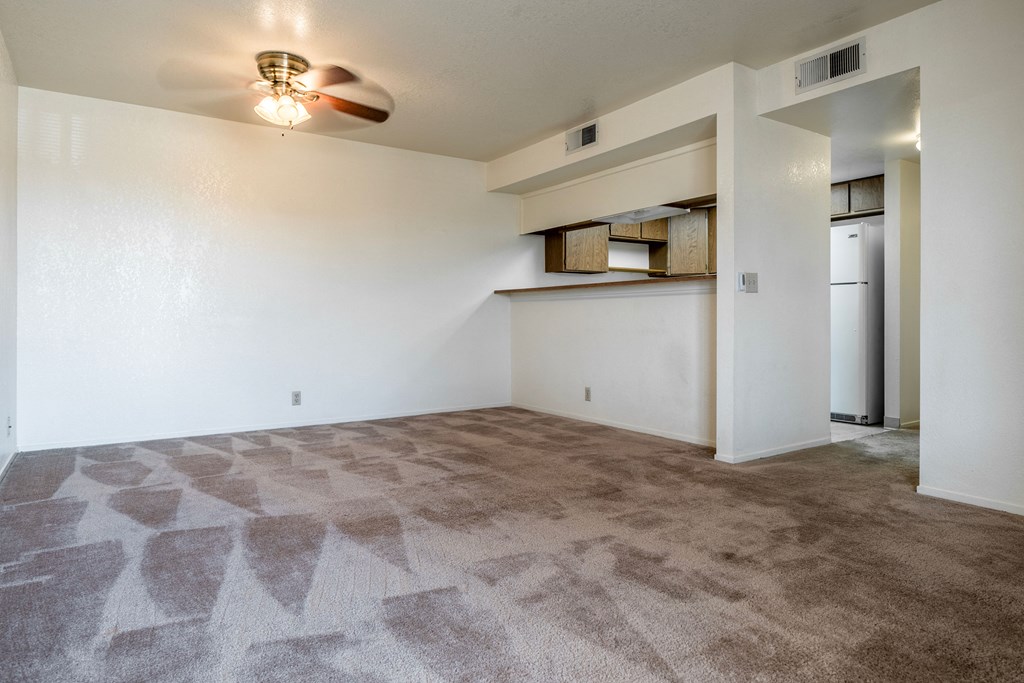 an empty living room with carpet and a ceiling fan