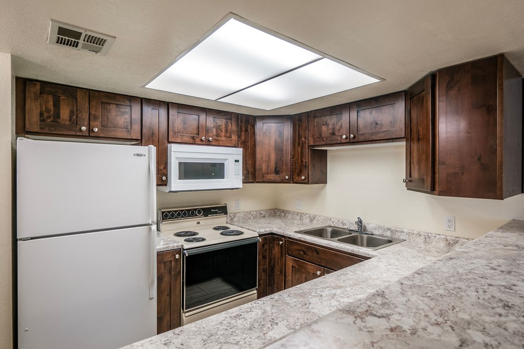 a kitchen with wooden cabinets and white appliances and granite counter tops
