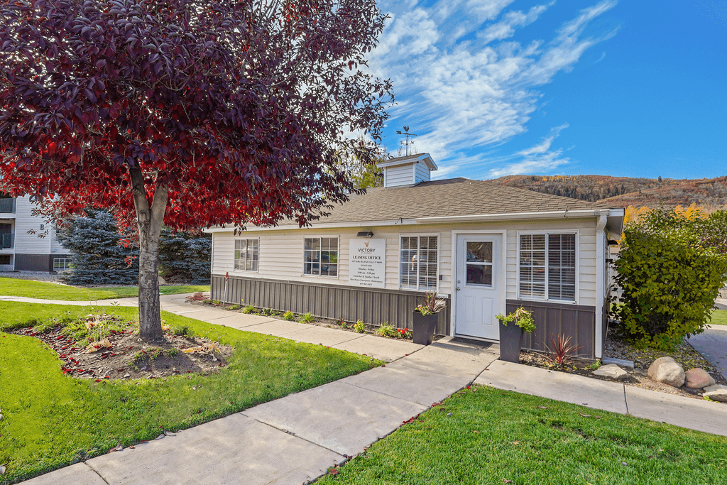 a white house with a tree and a sidewalk