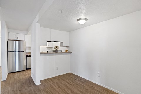 the living room and kitchen of an apartment with a stainless steel refrigerator