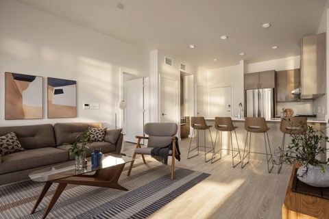 A modern living room with a grey sofa, wooden coffee table, and bar stools.