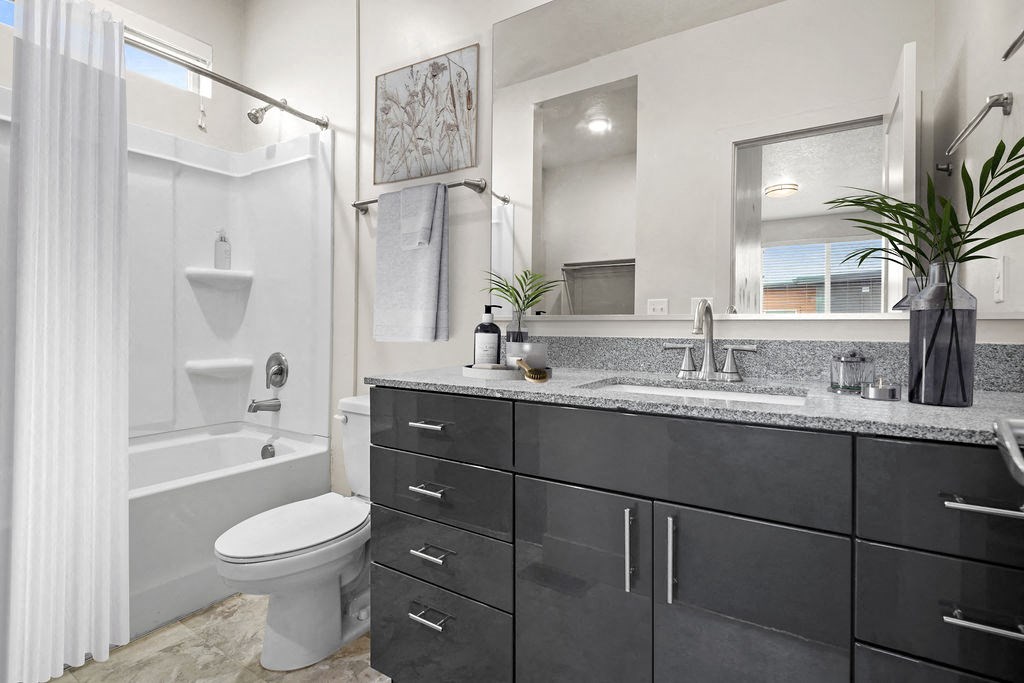 A bathroom with a white toilet, a white shower curtain, and a black cabinet.