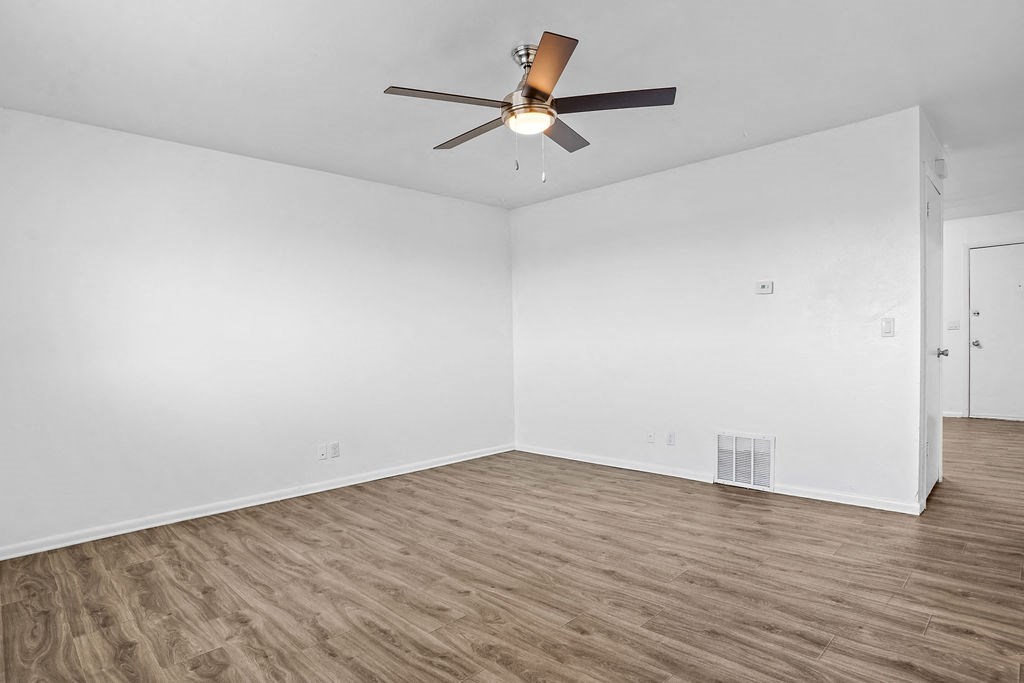an empty living room with white walls and a ceiling fan