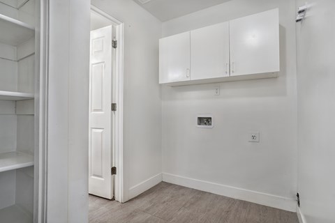 A white door is open to a room with white walls and a white cabinet.