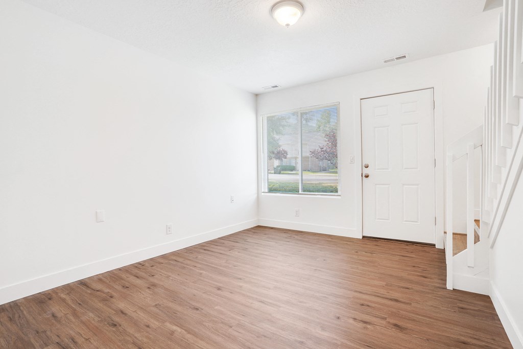 an empty living room with white walls and wood flooring