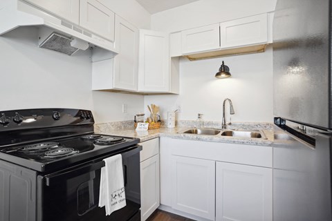 a kitchen with white cabinets and black appliances and a sink