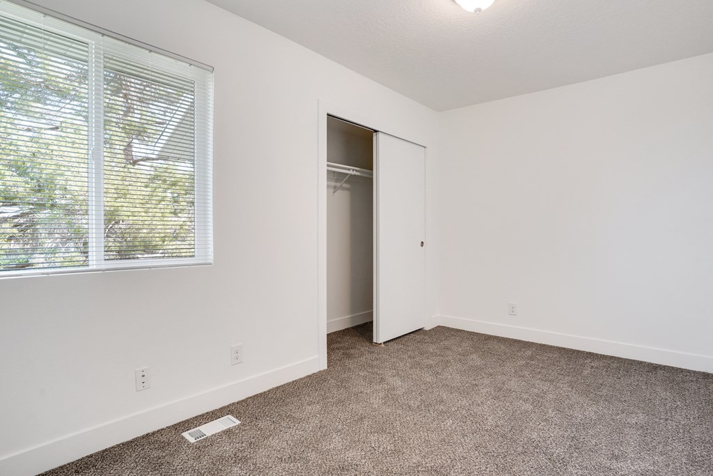 an empty bedroom with a large window and a closet