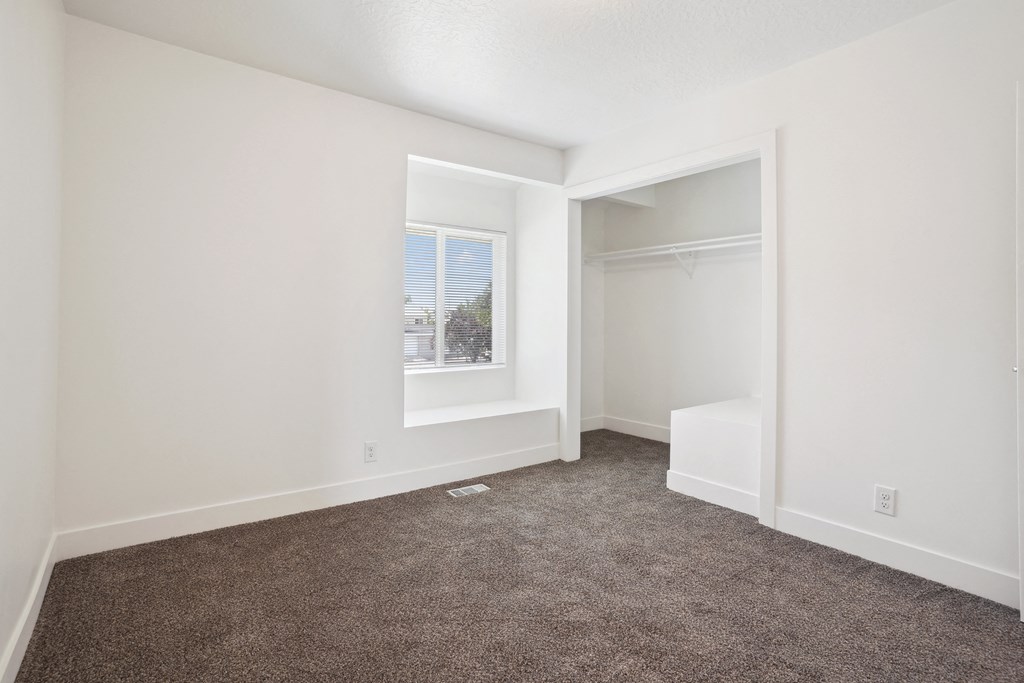 an empty room with carpet and a closet with a window