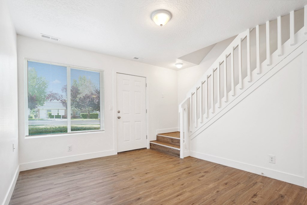 an empty living room with a staircase and a window