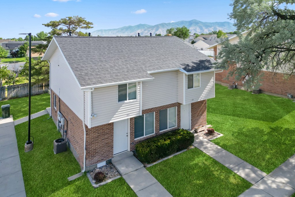 an aerial view of a white and brick house with a yard and grass