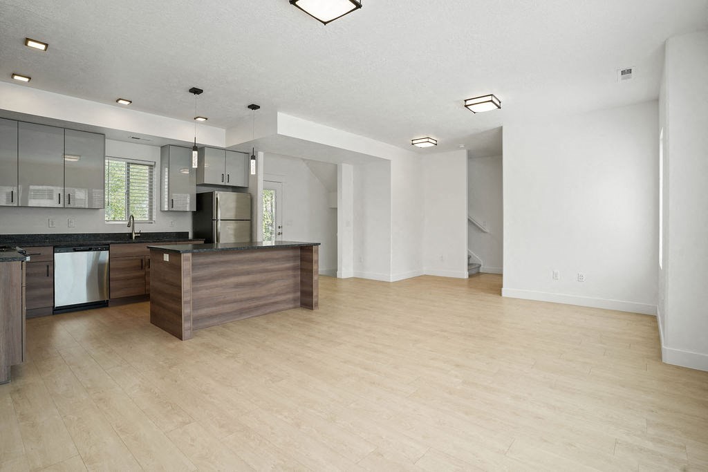 the living room and kitchen of an empty house with a wood floor