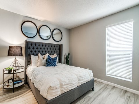 A bedroom with a large bed and a wall-mounted light fixture.