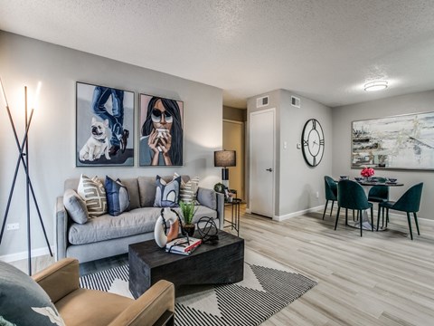 A living room with a grey couch, a coffee table, and a painting on the wall.