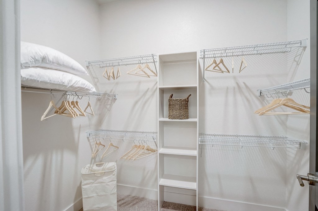 a closet with white curtains and white shelves and a bed with white pillows