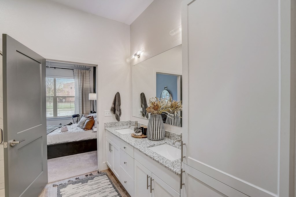 a bathroom with a sink and a mirror and a door to a bedroom