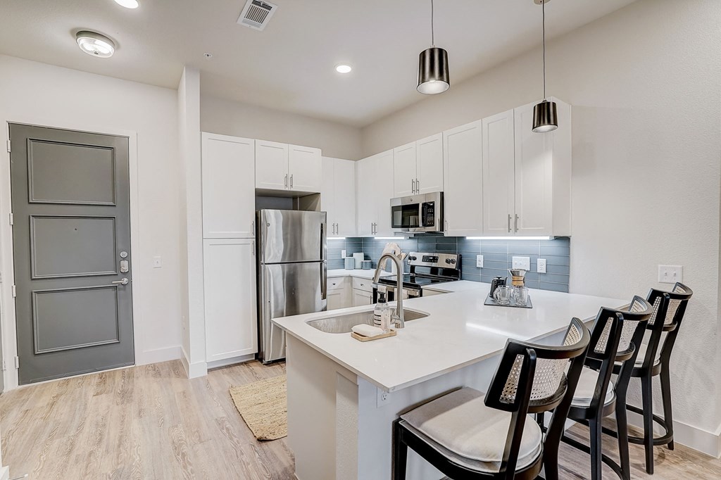 a kitchen with a white counter top and a stainless steel refrigerator