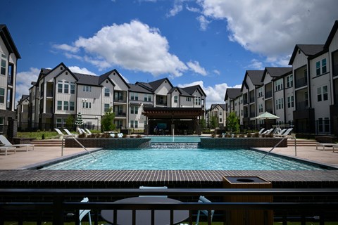 A large swimming pool in front of apartment buildings.