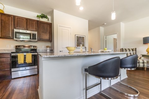 A kitchen with a white counter top and black chairs.