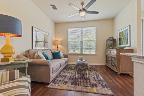A living room with a couch, a coffee table, and a ceiling fan.