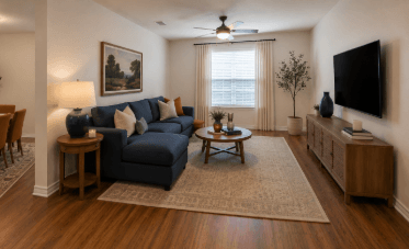 A living room with a blue couch and a television on the wall.