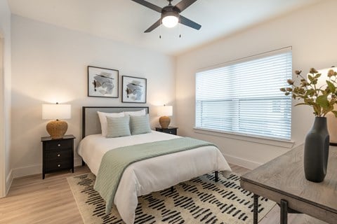 A bedroom with a bed, a ceiling fan, and a rug.