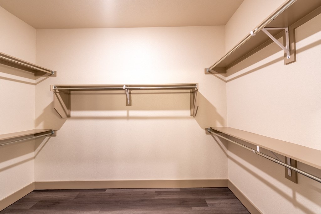 a walk in closet with white walls and a dark wood floor  at One Preston Station, Texas