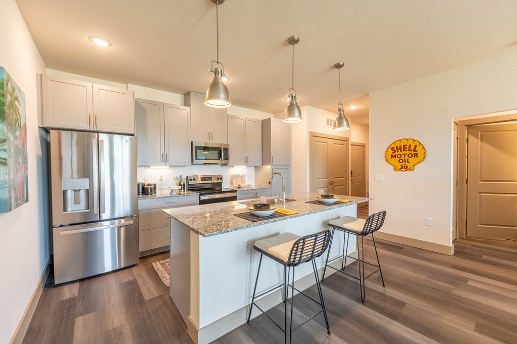 a kitchen with an island and two stools at One Preston Station, Celina