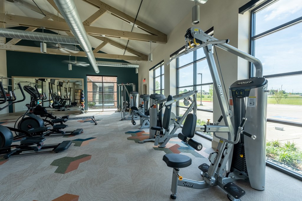 a gym with cardio equipment and a large window at One Preston Station, Celina