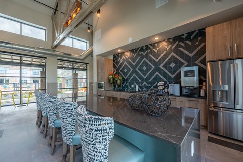 the kitchen has a large island with blue chairs and stainless steel appliances
