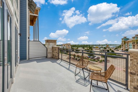 A balcony with two chairs and a table overlooking a cityscape.