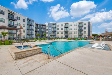 A large swimming pool in front of apartment buildings.