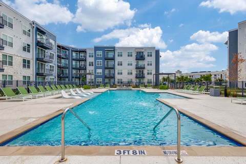 A swimming pool in front of apartment buildings.