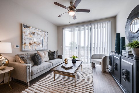 A living room with a grey couch, a coffee table, and a ceiling fan.