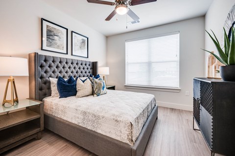 A bedroom with a bed, a ceiling fan, and a window with blinds.