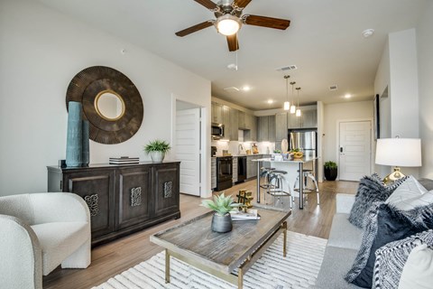 A living room with a white sofa, a wooden coffee table, and a large circular mirror on the wall.