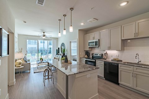 A kitchen with a large island and a ceiling fan.