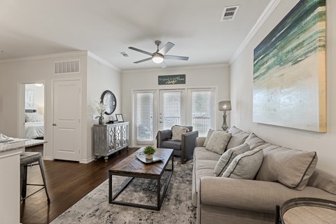 A living room with a couch, a coffee table, and a painting on the wall.