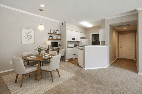 A dining room with a table set for two and a kitchen area in the background.