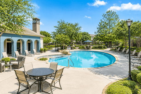 A pool with a table and chairs in front of a blue house.