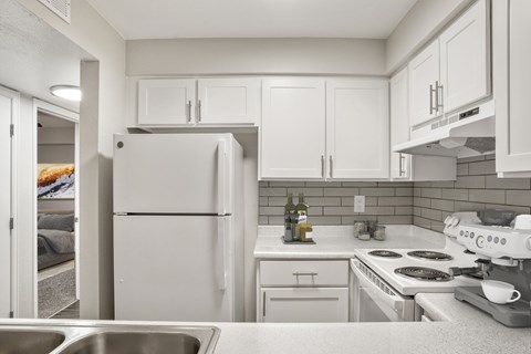 A kitchen with white cabinets and appliances.