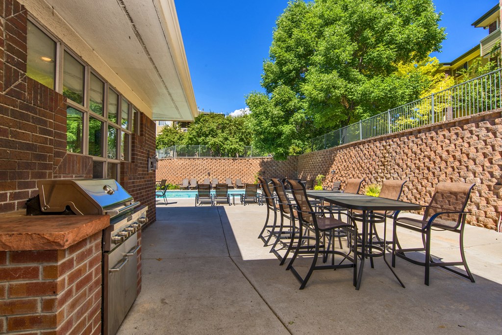 a patio with tables and chairs and a barbecue grill